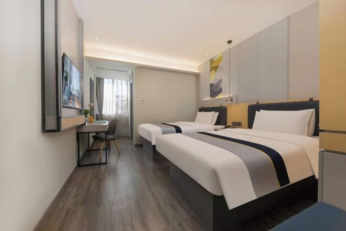 Hotellihuone, jossa on kaksi sänkyä, työpöytä ja tuoli.