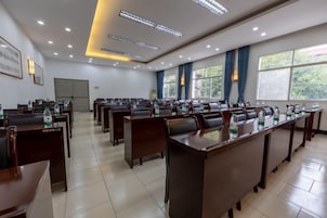 Un salón de conferencias con varias mesas y sillas, ventanas amplias e iluminación empotrada en el techo.