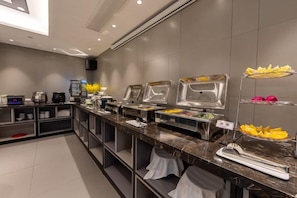 A buffet area with multiple serving stations, a coffee machine, and a speaker on the wall. - Homeinn Selected Hotel (Enshi Tusi City ) (Enshi City)