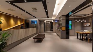 A modern hotel lobby with a reception desk, seating area, and a counter with digital displays. - Homeinn Selected Hotel (Enshi Tusi City ) (Enshi City)