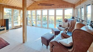 Une pièce spacieuse avec de grandes fenêtres, un canapé en cuir et un plafond en bois.