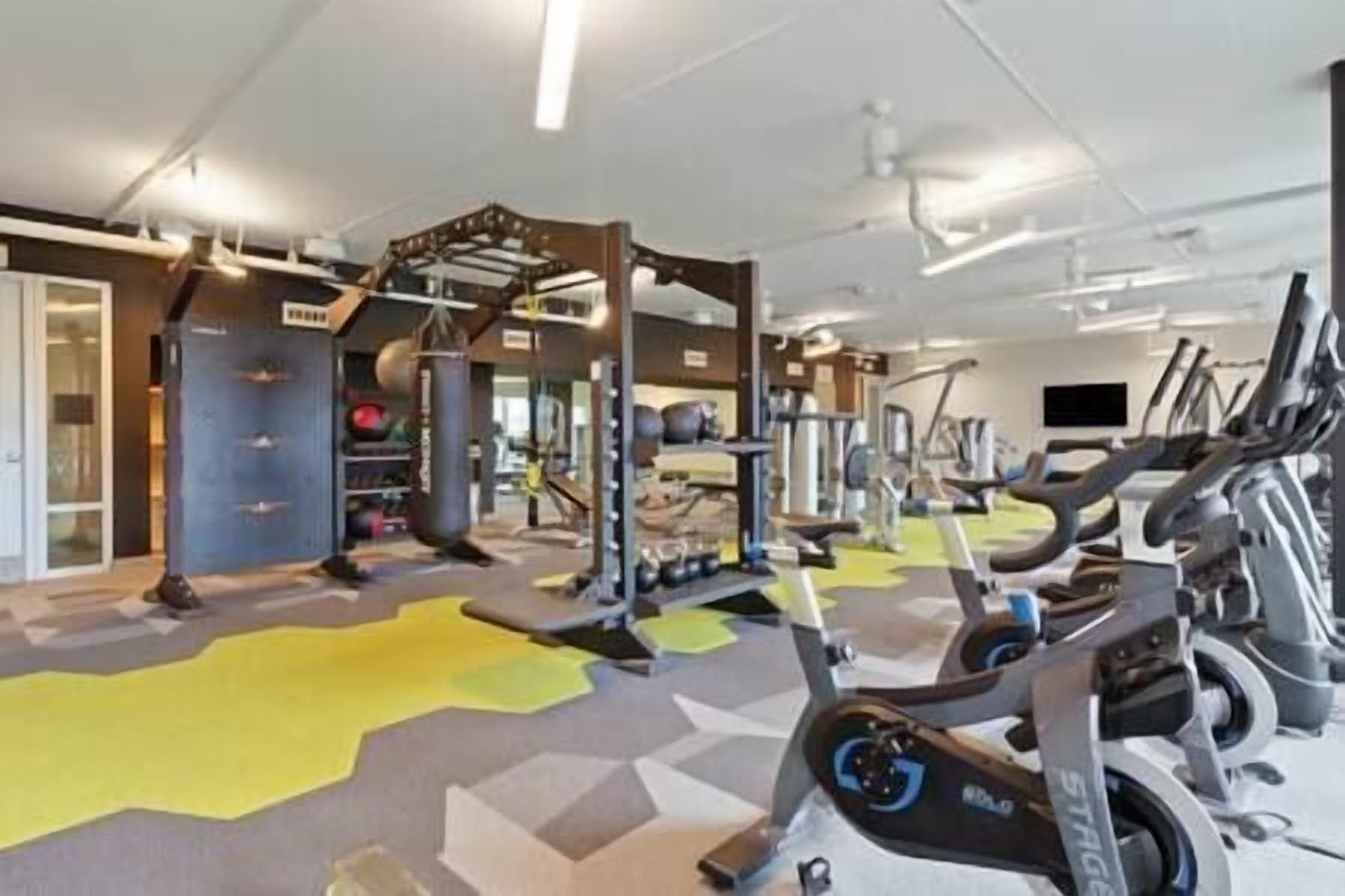 Ein Fitnessstudio mit verschiedenen Trainingsgeräten, darunter Laufbänder und Kraftgeräte.