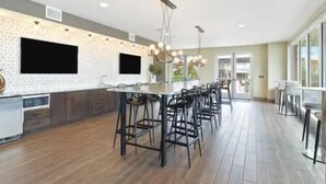 Une cuisine moderne dotée d’un îlot central, de tabourets de bar et de luminaires suspendus.
