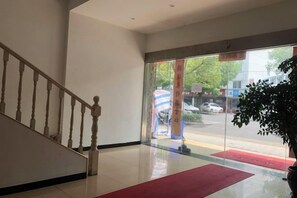 A hotel lobby with a staircase, a red carpet, and a view of the street outside. - Changwei Hotel (Shanghai)