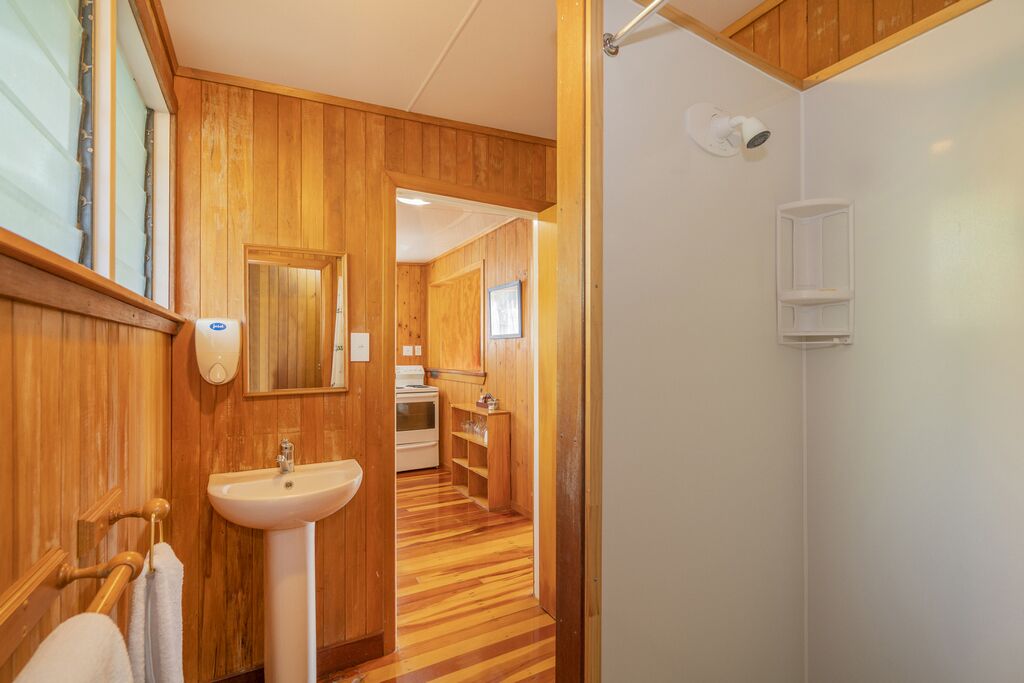 Une salle de bain aux finitions en bois, comprenant un lavabo, un miroir et un porte-serviettes.