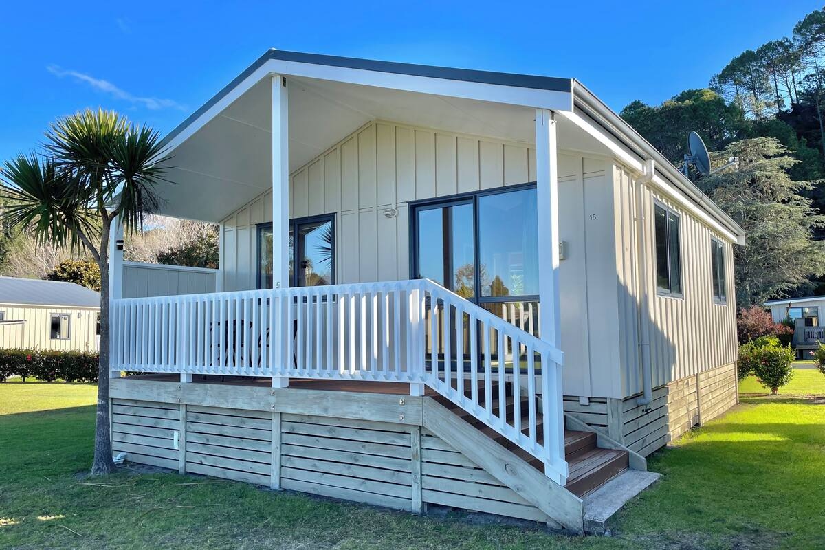 Une maison mobile de plain-pied, dotée d’un porche couvert et d’un petit escalier menant à l’entrée.