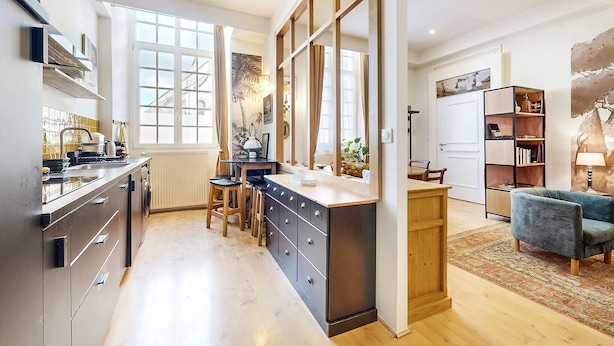 A modern kitchen with a central island, a dining area with a blue sofa, and a bookshelf. - 1 bedroom cozy apartment in Lons-Le-Saunier (Lons-Le-Saunier)
