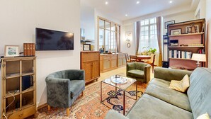 A modern living room with a sofa, armchairs, a coffee table, and a TV. - 1 bedroom cozy apartment in Lons-Le-Saunier (Lons-Le-Saunier)