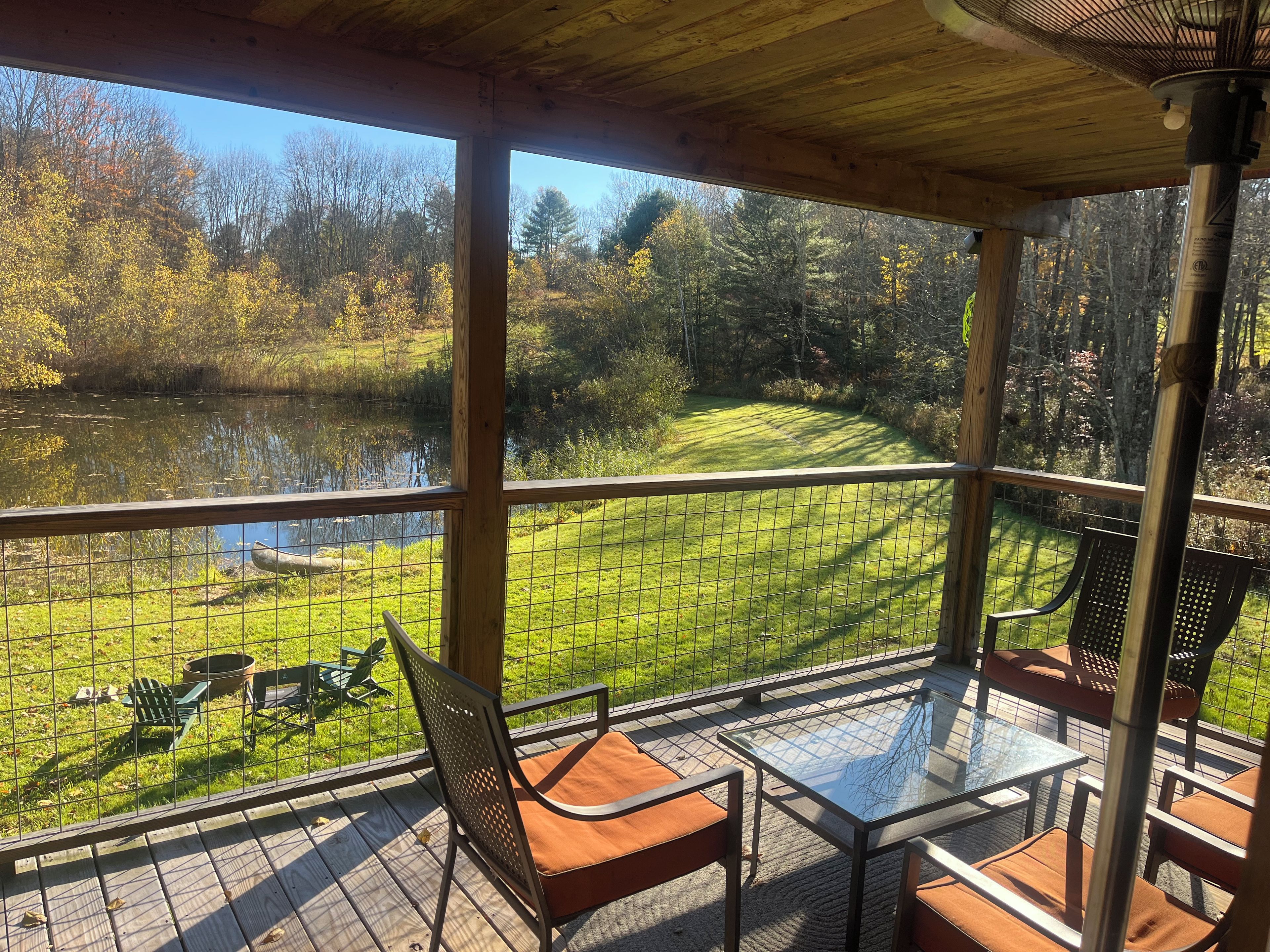 Un espace extérieur abrité, aménagé avec des sièges, et offrant une vue sur un lac et une forêt.