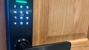 Een digitaal keypad slot met verlichte cijfers en een kaartsleuf, bevestigd aan een houten deur.