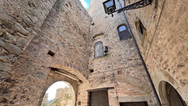 An arched stone corridor with a wooden door and a small window with a bell. - Pet friendly apartment (Gualdo Cattaneo)