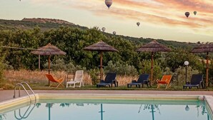 A pool with lounge chairs and umbrellas, surrounded by greenery and hills. - Pet friendly apartment (Gualdo Cattaneo)