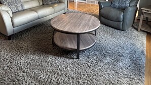 Una sala de estar con sofá, sillón, mesa de centro redonda y ventilador de techo.