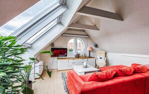 A loft-style room with a red sofa, a white desk, and a large window. - Gorgeous apartment in Helsingborg with WiFi (Helsingborg)