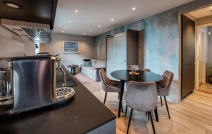 A modern kitchen with a coffee maker, a dining table with chairs, a sofa, and a door leading to another room. - Gorgeous apartment in Helsingborg with WiFi (Helsingborg)