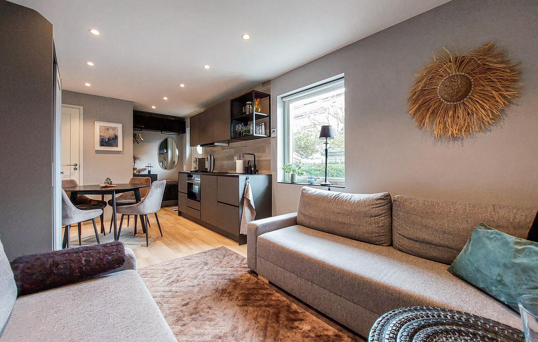 Ett kompakt bostadsutrymme med ett litet kök, en matplats och en soffa.