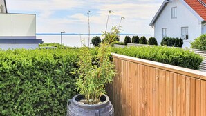 A rooftop garden with a wooden fence, a potted bamboo plant, and a view of the sea. - Gorgeous apartment in Helsingborg with WiFi (Helsingborg)