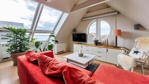 A modern loft bedroom with a large skylight, a television, a round mirror, and a cozy red sofa. - Gorgeous apartment in Helsingborg with WiFi (Helsingborg)