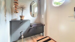 A modern entryway with a grey console, a potted plant, a mirror, and a small bench. - Gorgeous apartment in Helsingborg with WiFi (Helsingborg)