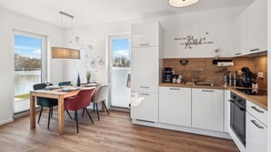 Une cuisine moderne avec des meubles blancs, un plan de travail en bois et un coin repas comprenant une table et des chaises.