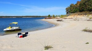 Une plage avec un bateau, une glacière et une chaise.