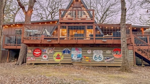 Une cabane avec une façade en bois, plusieurs terrasses et un grand panneau d’affichage arborant divers logos de marques.