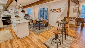 Une cuisine spacieuse avec des poutres apparentes, un coin repas doté d’un grand îlot central et un bar avec des tabourets.
