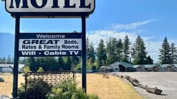 A sign for Glacier Inn Motel with amenities listed including beds, rates, family rooms, and Wifi - Cable TV.