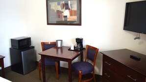 Una habitación de hotel compacta con una pequeña kitchenette, una mesa de comedor con dos sillas, un televisor y un espejo en la pared.