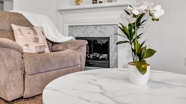 A living room with a beige sofa, a white vase with white flowers, and a fireplace. - 3-bedroom house in charming College Park with WiFi, AC /ATL airport 10 minutes (College Park)
