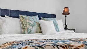 A neatly made bed with a patterned bedspread, a blue headboard, and a lamp on a bedside table. - 3-bedroom house in charming College Park with WiFi, AC /ATL airport 10 minutes (College Park)