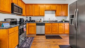 A kitchen with wooden cabinets, stainless steel appliances, and a granite countertop. - 3-bedroom house in charming College Park with WiFi, AC /ATL airport 10 minutes (College Park)