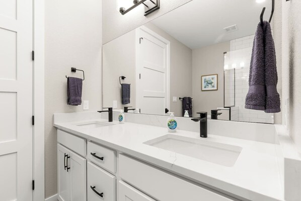 Une salle de bain moderne avec deux lavabos, un grand miroir et un porte-serviettes.