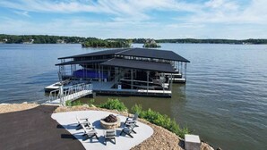 Un muelle a orillas del lago con una zona de estar cubierta y sillones de descanso.