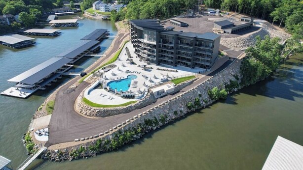 Un hotel frente al agua con piscina, muelle y zona de estacionamiento.