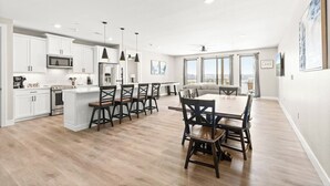 Una cocina moderna con gabinetes blancos, una isla central e iluminación colgante.