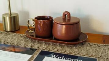 A tea set on a table with a burlap placemat and a welcome sign.