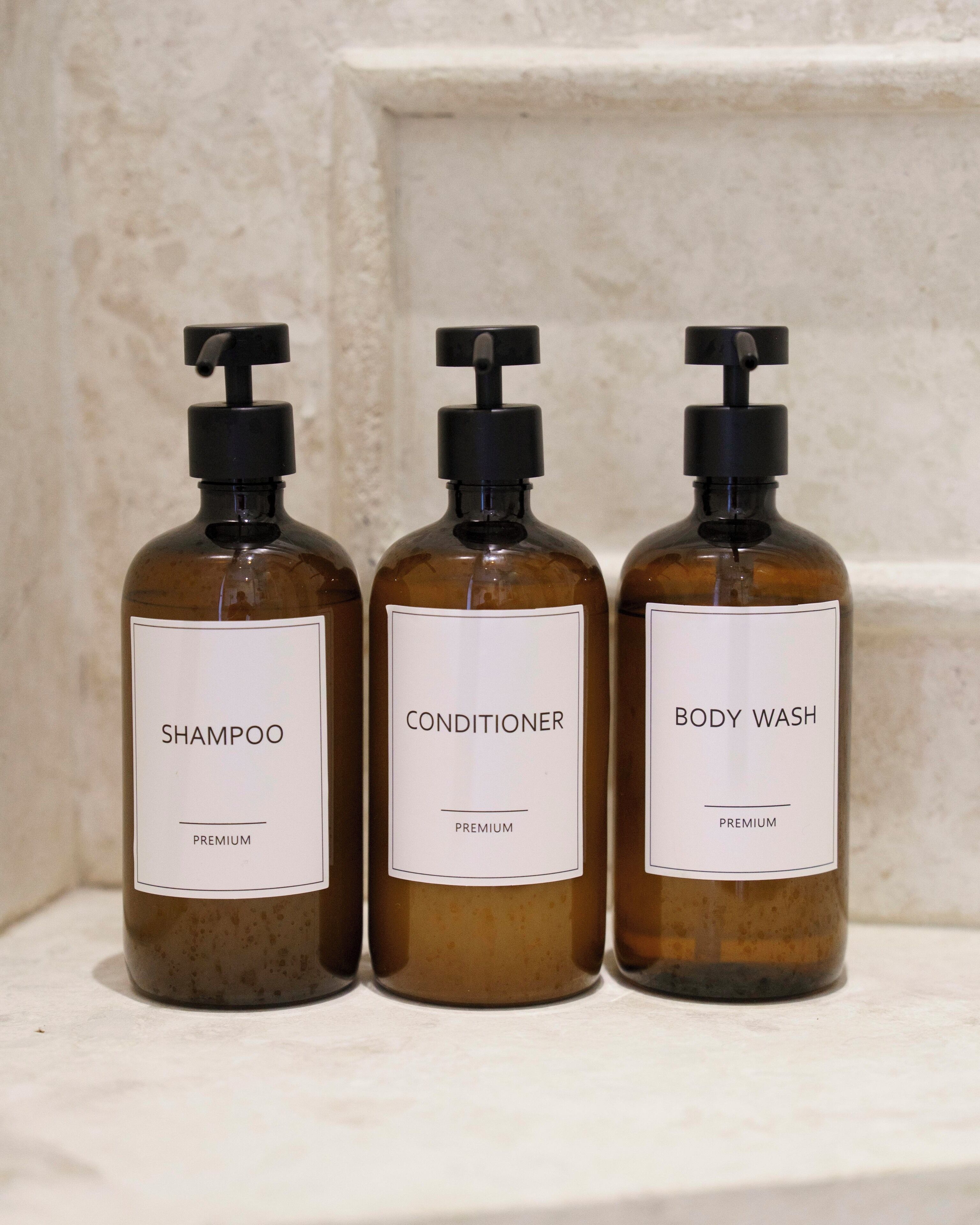 Drei Flaschen Shampoo, Spülung und Duschgel auf einem Regal.