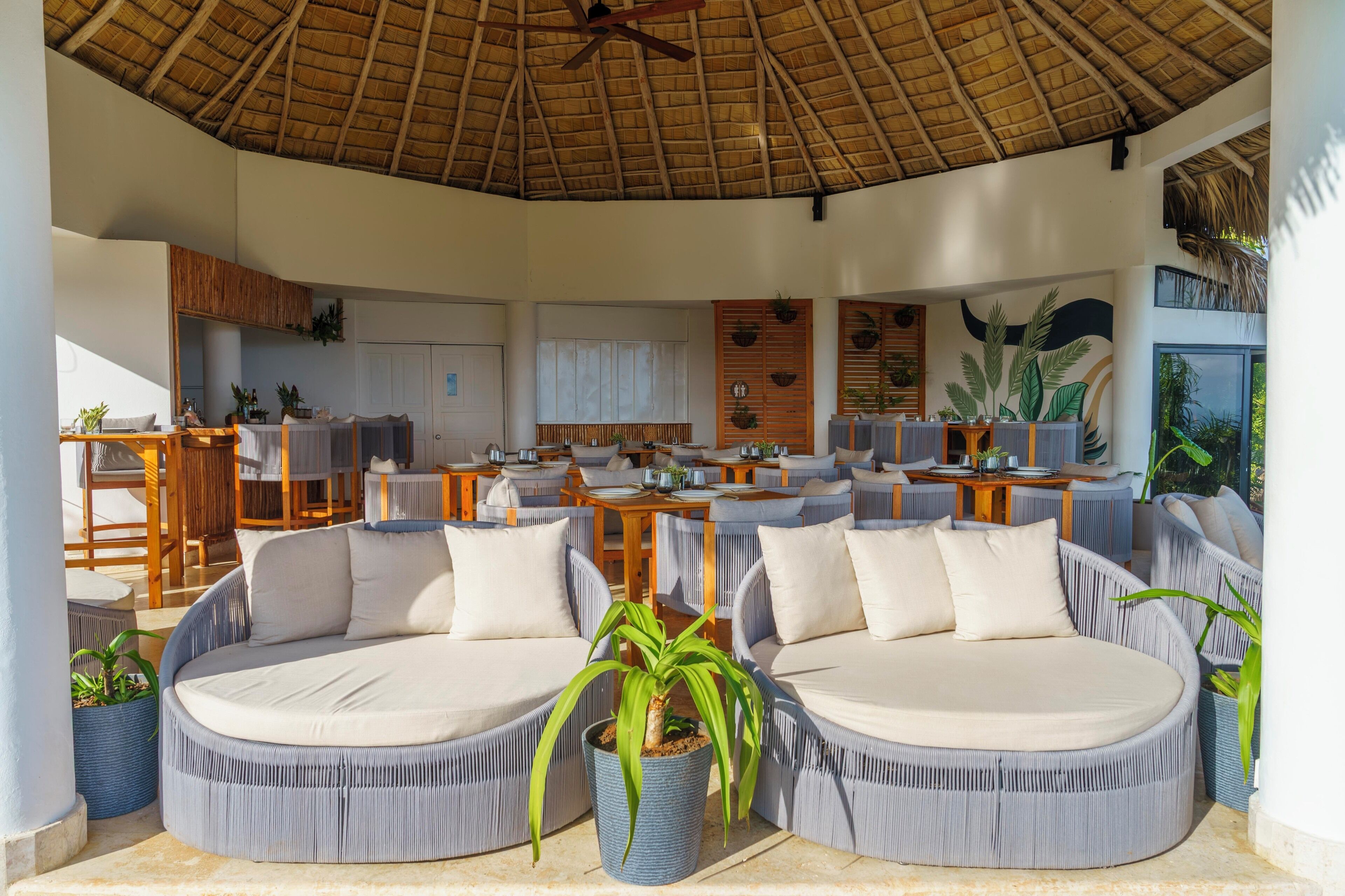 A spacious outdoor lounge area with round seating and a thatched roof.