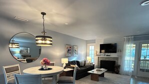 A modern living room with a dining area, a fireplace, and a flat-screen TV. - Reduced fall rates! Evian.Sleeps 6 2BR 2.5 bath free pickleball, tennis & pool. (Hilton Head Island)