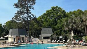 A swimming pool with lounge chairs and umbrellas, surrounded by trees and a building with a tiled roof. - Reduced fall rates! Evian.Sleeps 6 2BR 2.5 bath free pickleball, tennis & pool. (Hilton Head Island)