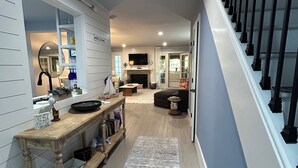 A modern interior with a wooden console table, a fireplace, a staircase with black railings, and a view of the outdoors. - Reduced fall rates! Evian.Sleeps 6 2BR 2.5 bath free pickleball, tennis & pool. (Hilton Head Island)