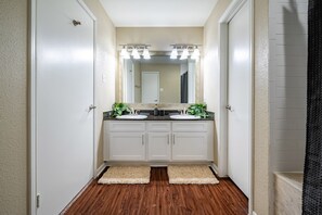 A bathroom with two sinks, a large mirror, and a light fixture above the mirror.