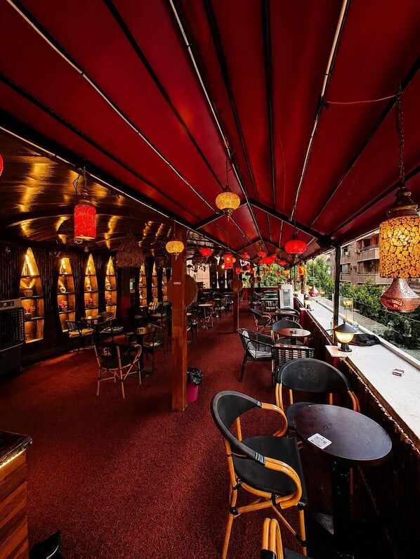 An indoor dining area with tables and chairs, red ceiling, and hanging lanterns.