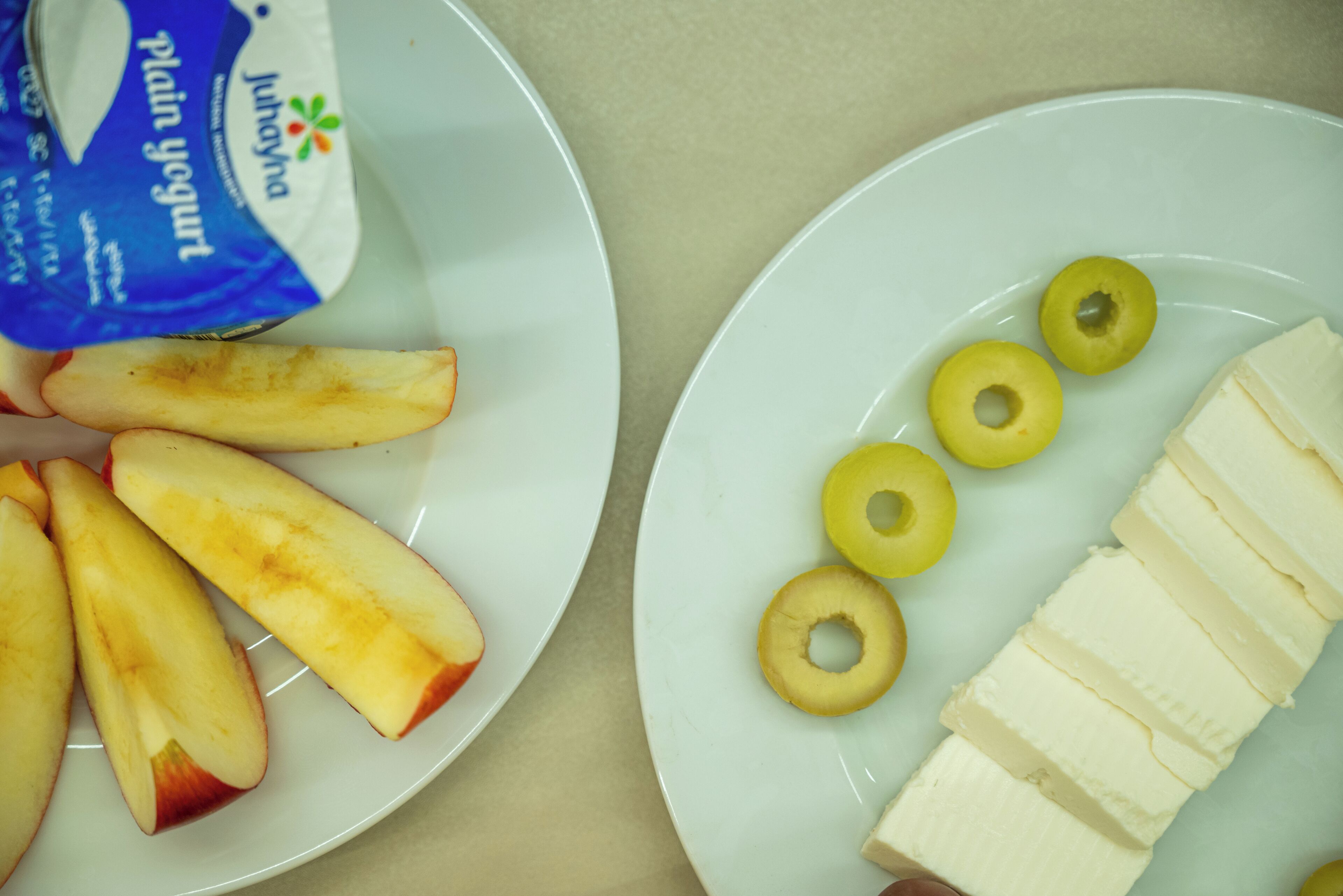 Zwei Teller mit Apfelscheiben und Bananen, sowie ein Becher Naturjoghurt.