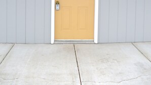 A single-story building with a yellow door, white trim, and a gray exterior wall. - #15 ONE QUEEN BED with WiFi and AC in charming Columbia Falls, 20 mi from GNP!! (Columbia Falls)