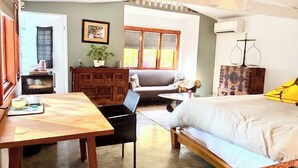 Una habitación acogedora con cama, escritorio, silla, sofá y ventana con persianas.