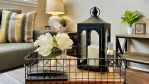 Una sala de estar acogedora con un sofá, una lámpara, un farol decorativo y una mesita con una planta.