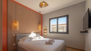 A bedroom with a bed, a window, and a television on the wall.