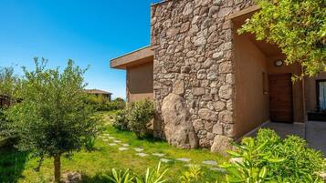 A stone building with a modern design, a paved pathway, and greenery.